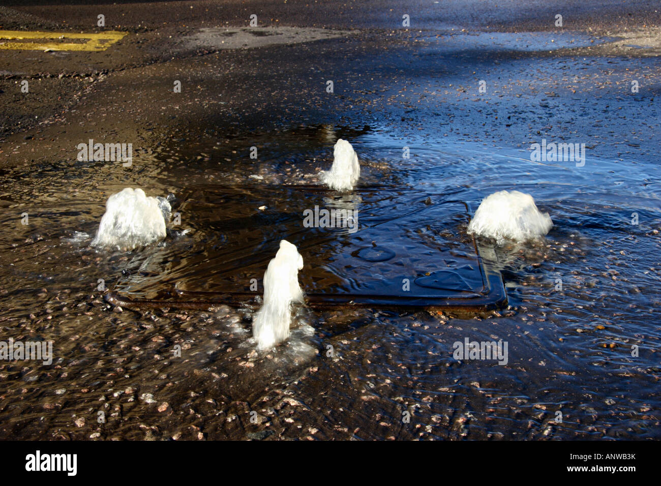 Water squirting up out of a road drain. Stock Photo
