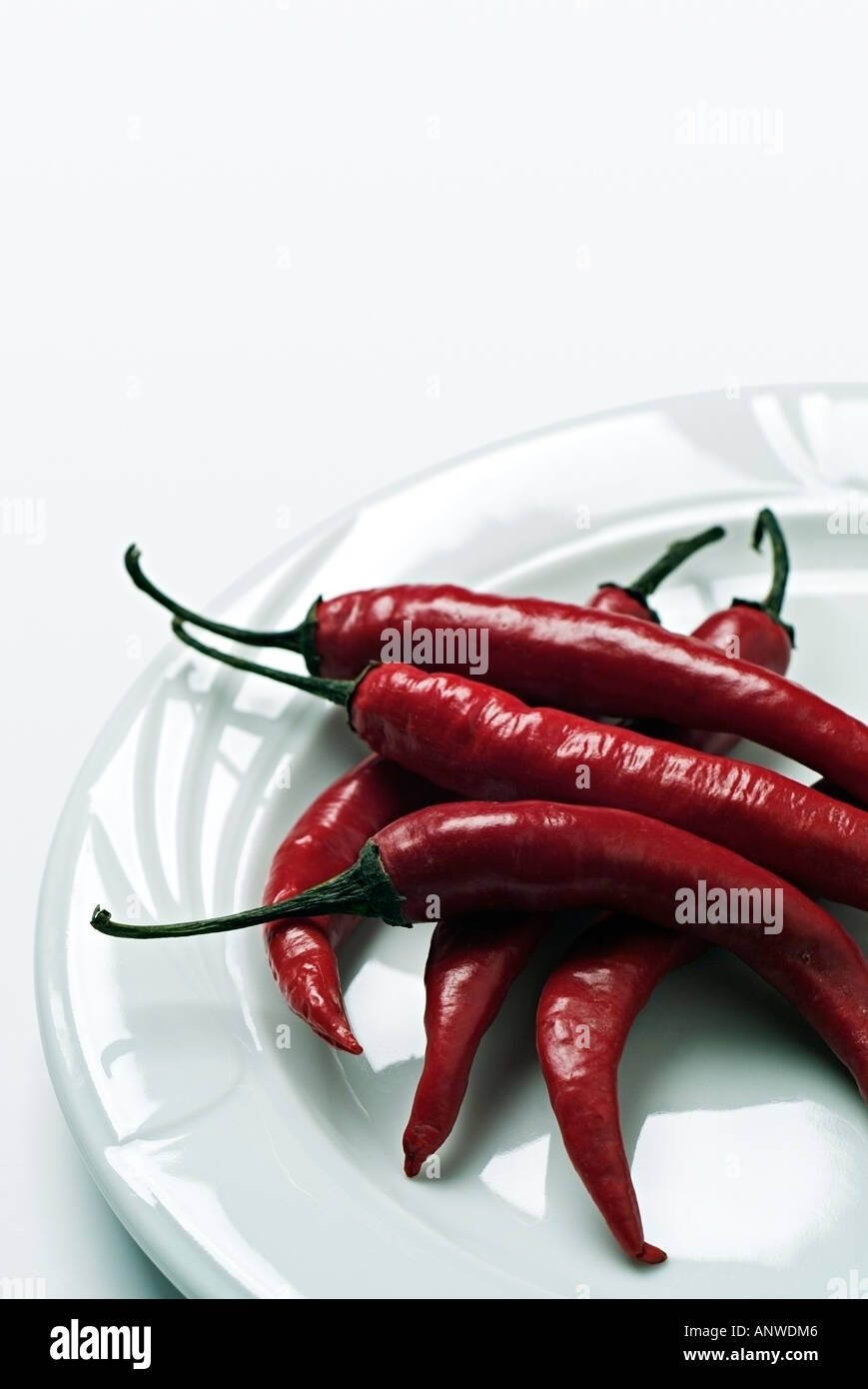 Red Chili Peppers on a Plate Against a White Background Capsicum Annum Stock Photo