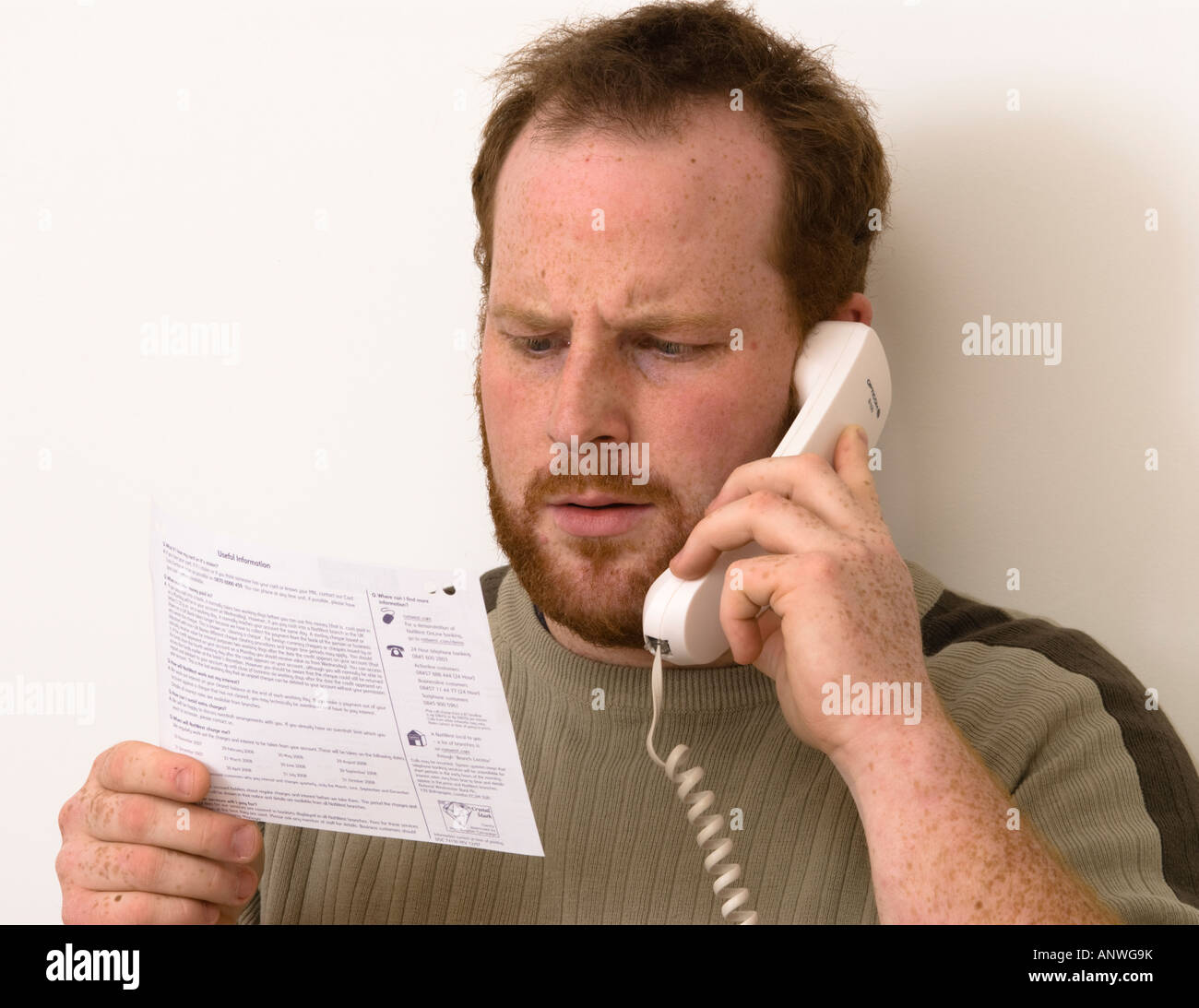 man on phone questioning items on his bank statements showing startled surprise or horror Stock Photo