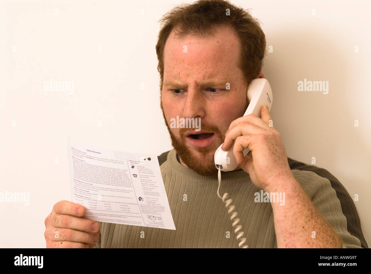 man on phone questioning items on his bank statements showing startled surprise or horror Stock Photo