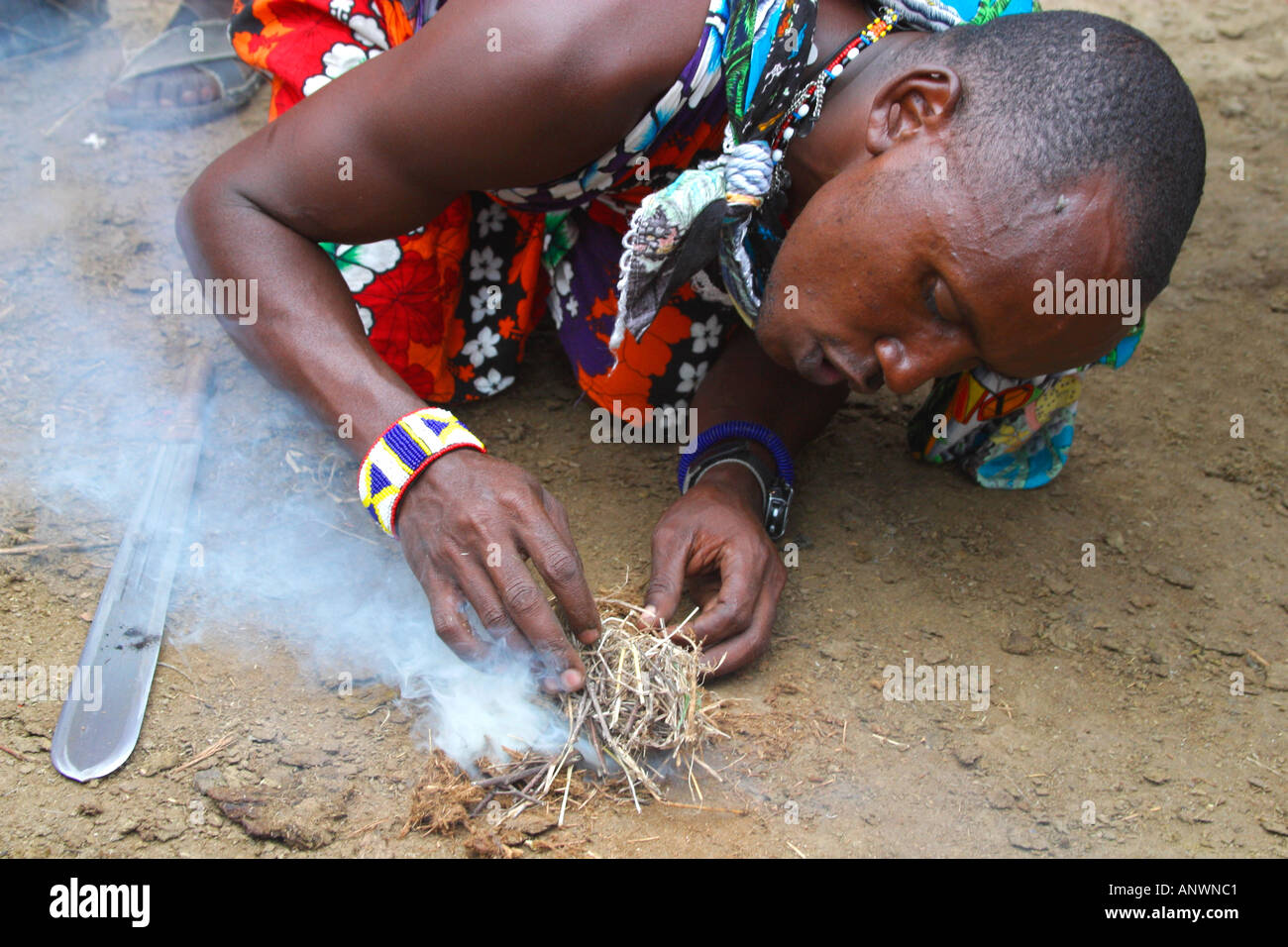 Maasai warrior making fire in village in Masai Mara National Nature Reserve Kenya East Africa Stock Photo