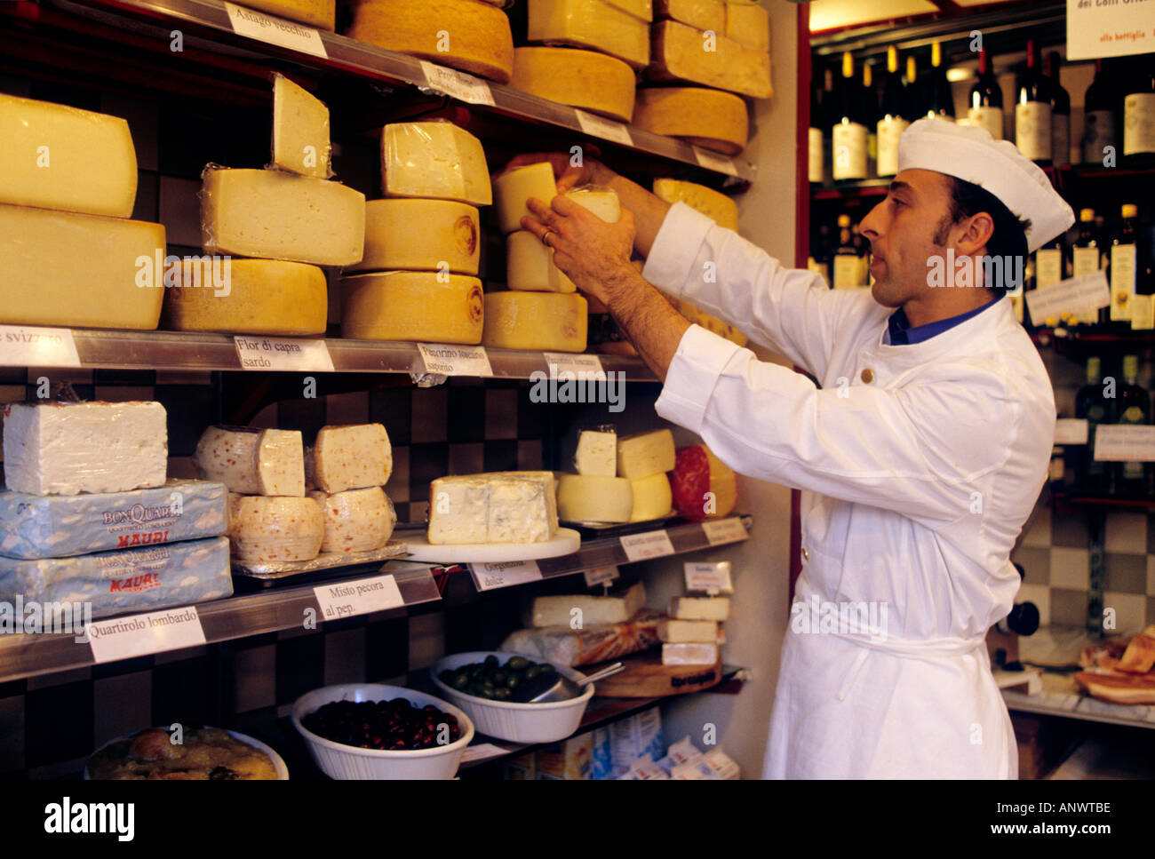 Italian Delicatessen Tuscany, deli produce shopkeeper setting out display of local Parmigiano Reggiano regional cheeses Siena Tuscany Italy Stock Photo