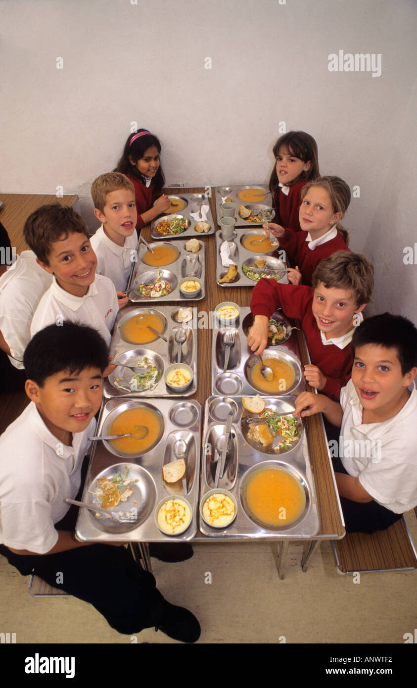 MULTICULTURAL HEALTHY SCHOOL MEALS DINNERS Group of multi ethnic junior school students having healthy balanced lunch in school canteen Stock Photo