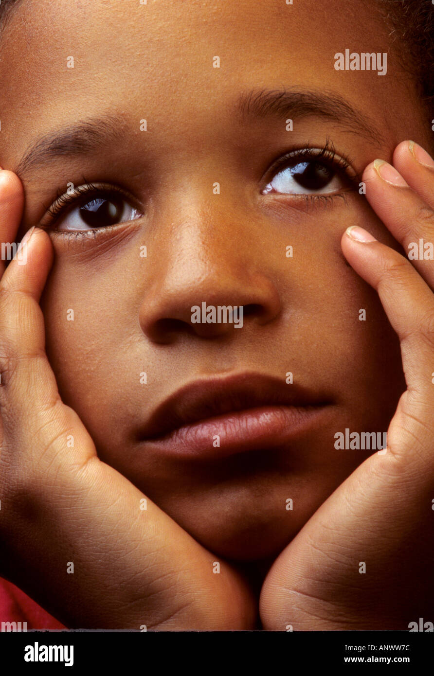 Sad Afro Caribbean 8yrs to 10yrs boy with his head in his hands Stock Photo