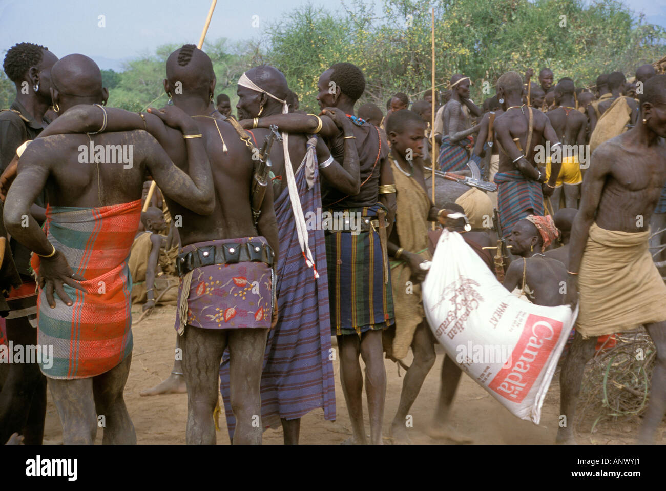 Africa, Ethiopia, Omo river region, Mursi warriors guard the villagers that come out to get food from a Swedish missionary Stock Photo