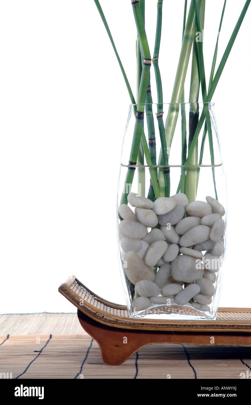 Bamboo and grasses in a white stone filled vase set upon a organic  zen tray. Stock Photo
