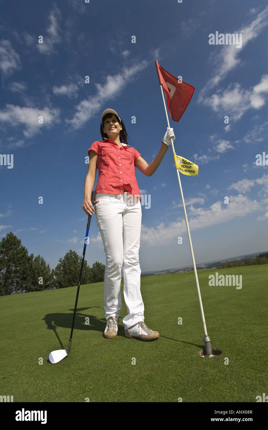 female golfer with club takes the flag out of the hole Stock Photo Alamy