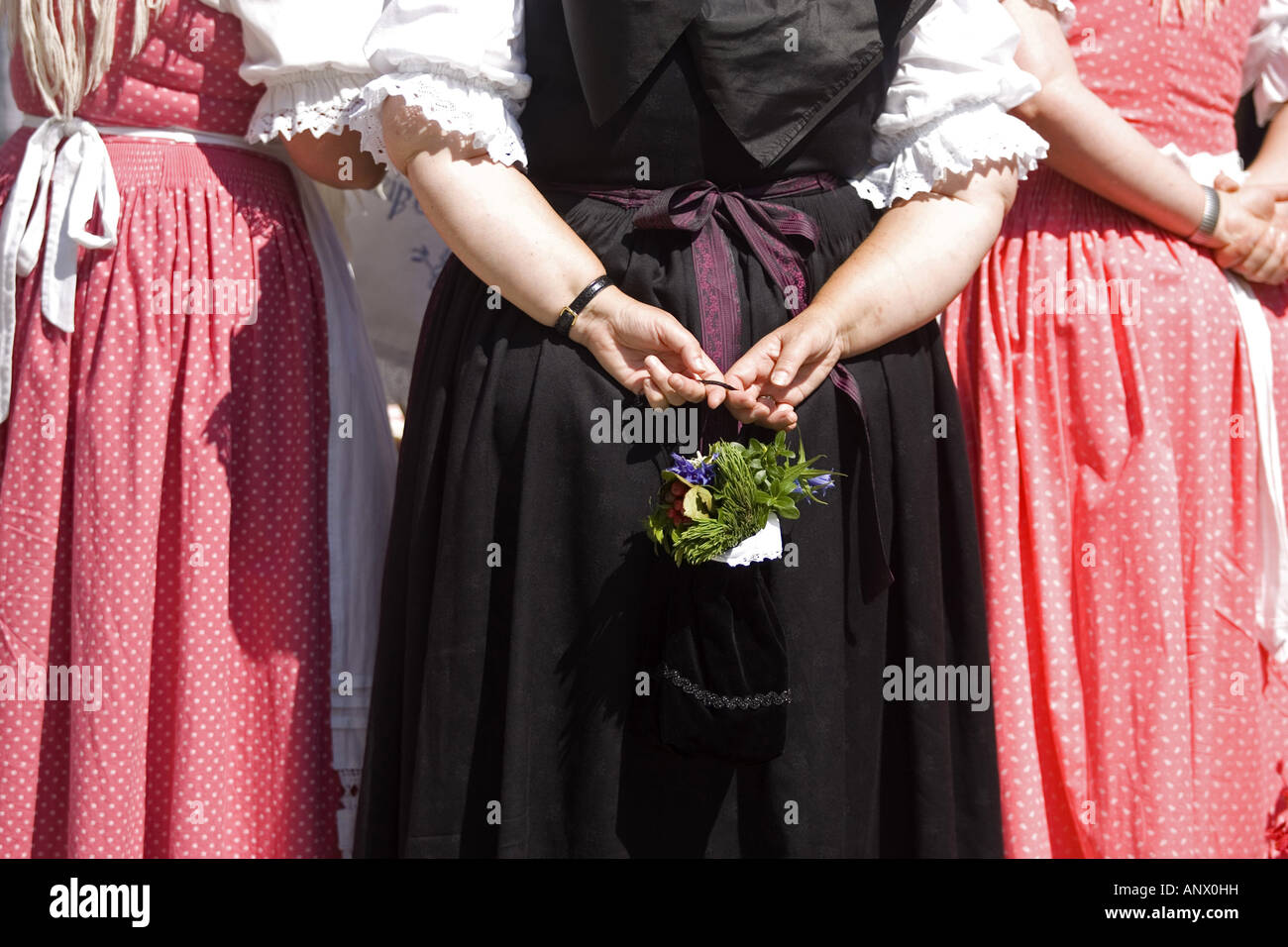 woman in a dirndl holding a bunch of flowers behind her back at the Gamsbarttag in Goisern, Austria, Oberoesterreich Stock Photo