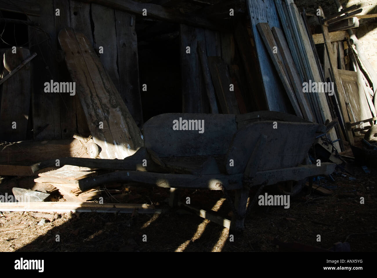 Stock Photo of an old wooden wheelbarrow abandoned inside an old french barn Stock Photo
