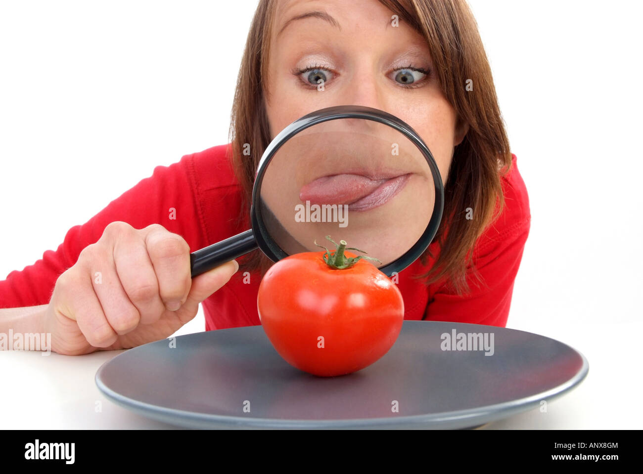 woman with magnifying glass viewed tomato at plate Stock Photo
