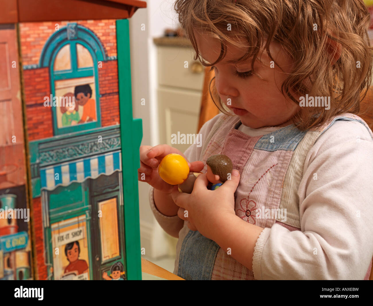 Two Year Old Playing with Toy People and Dolls House Stock Photo