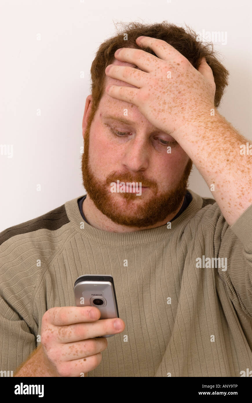 man looking at mobile phone with a concerned worried look on his face