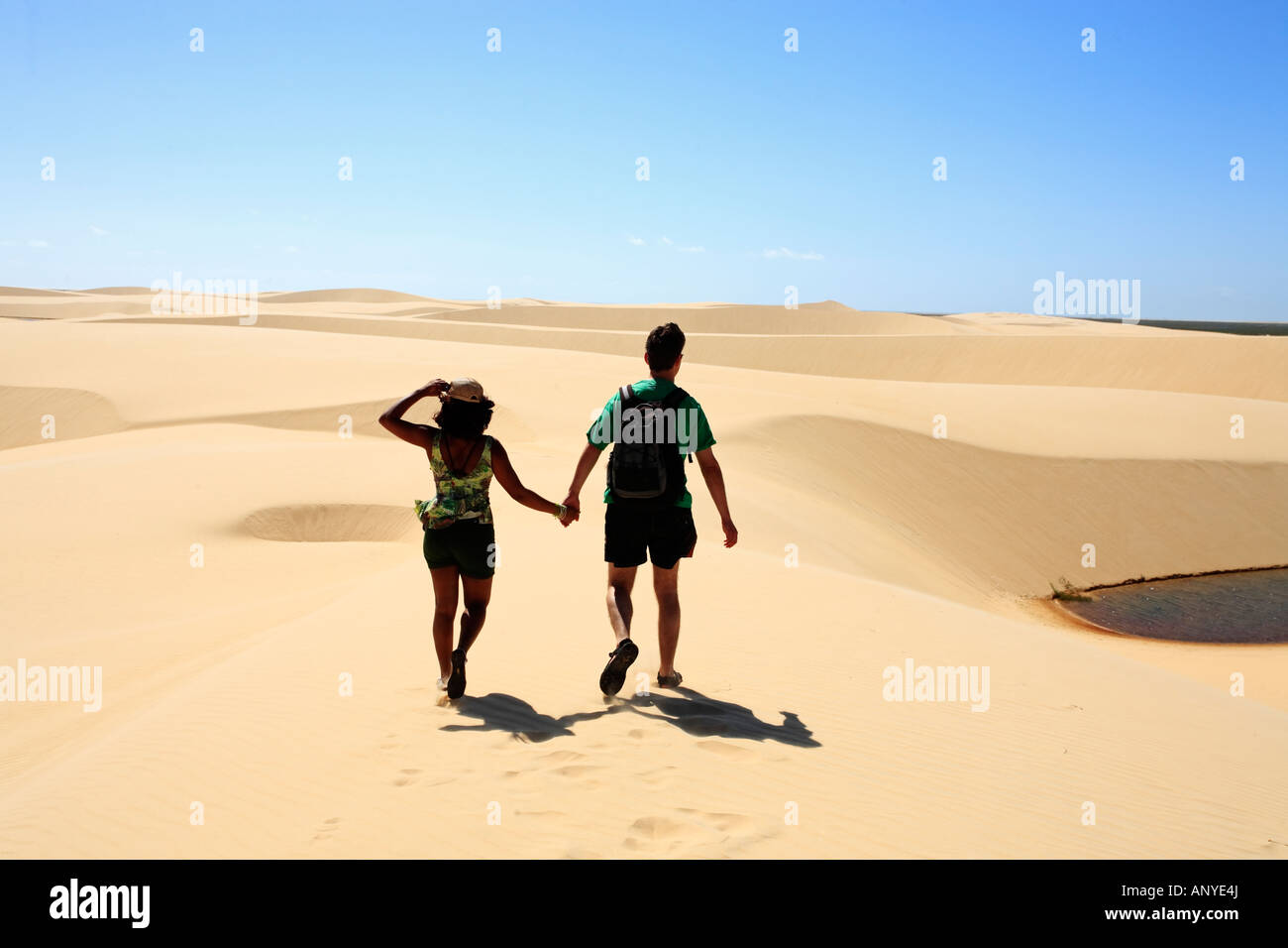 couple walking hand in hand on the desert sand dunes of the Lencois Maranheses National Park Stock Photo