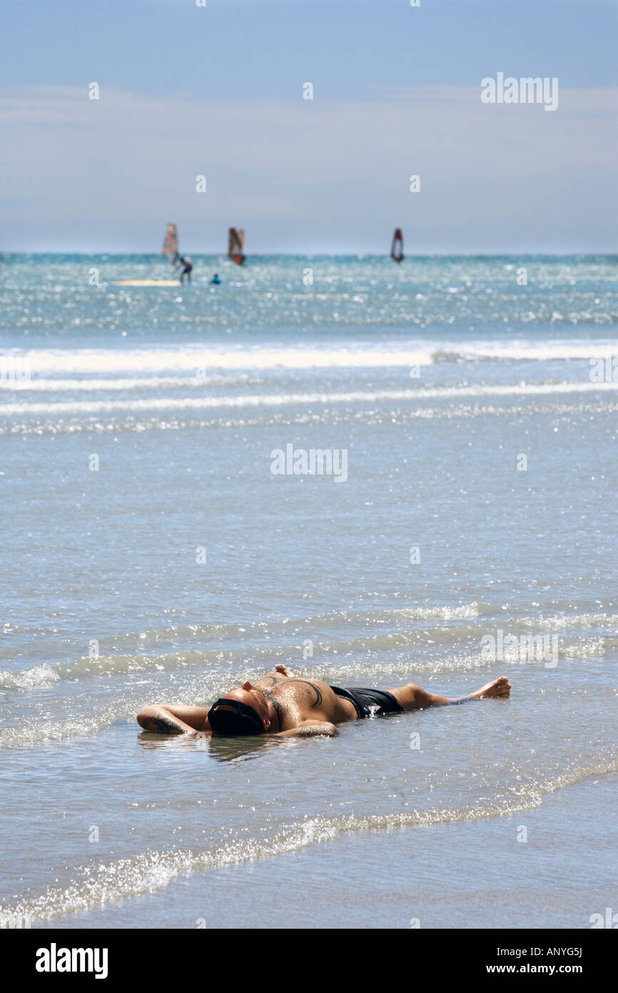 man sunbathing in the water of the beach in the beautiful fisherman village of Jericoacoara in ceara state brazil Stock Photo
