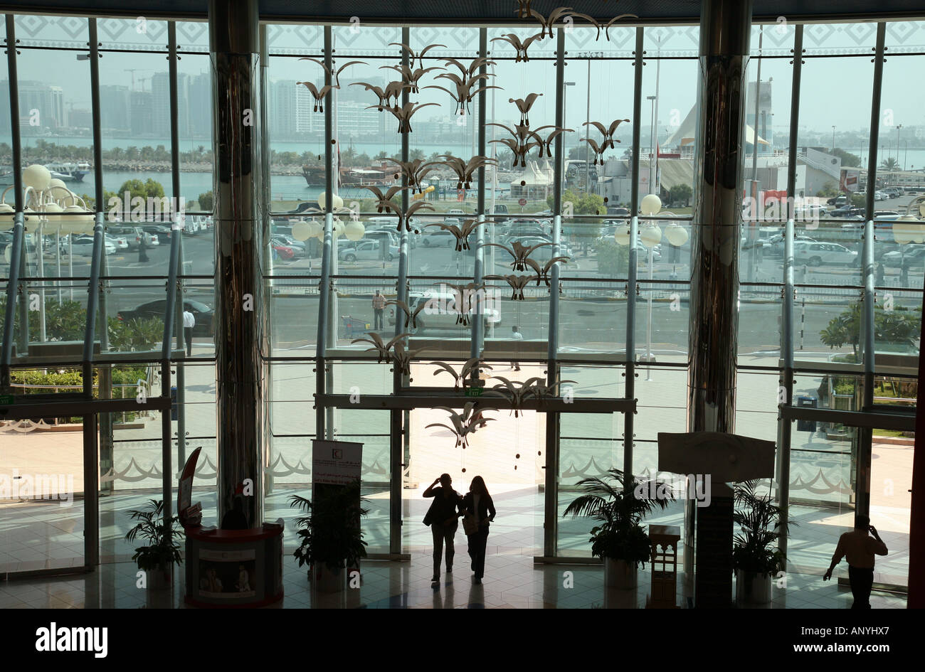 A couple enter the 'Marina Mall', Abu Dhabi city, silhouetted against the huge glass frontage of the Mall Stock Photo
