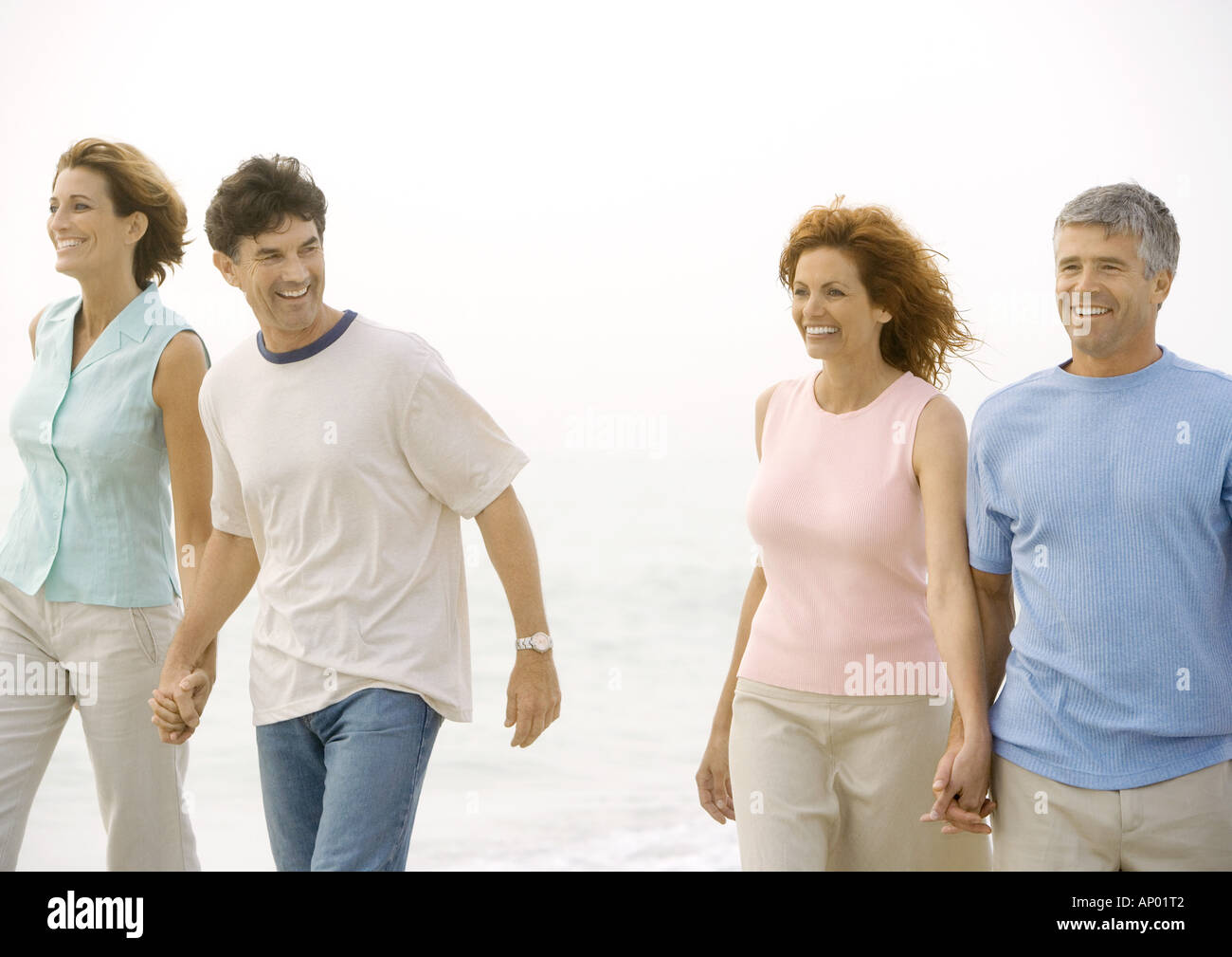 Two mature couples walking on beach Stock Photo