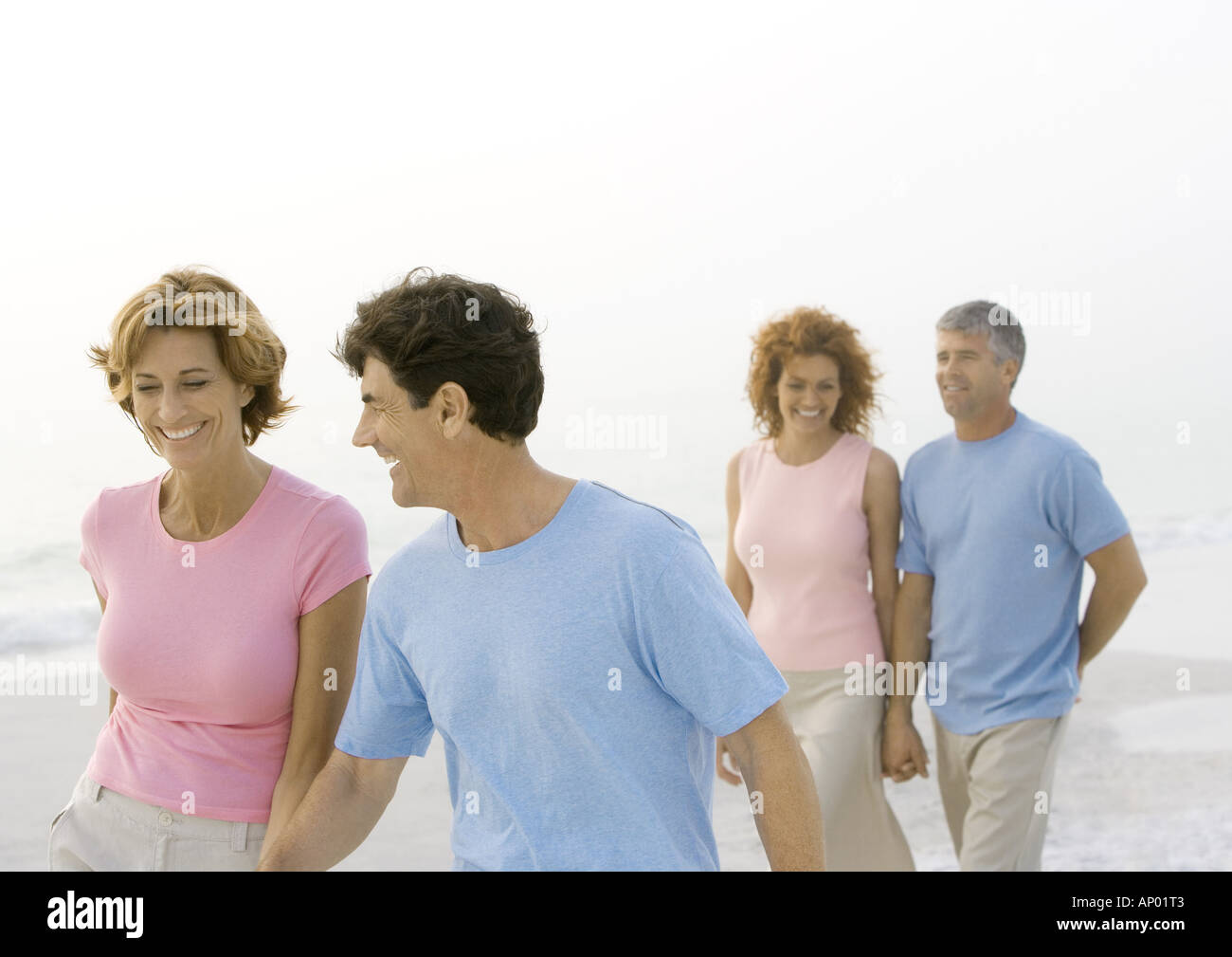 Two mature couples walking on beach Stock Photo