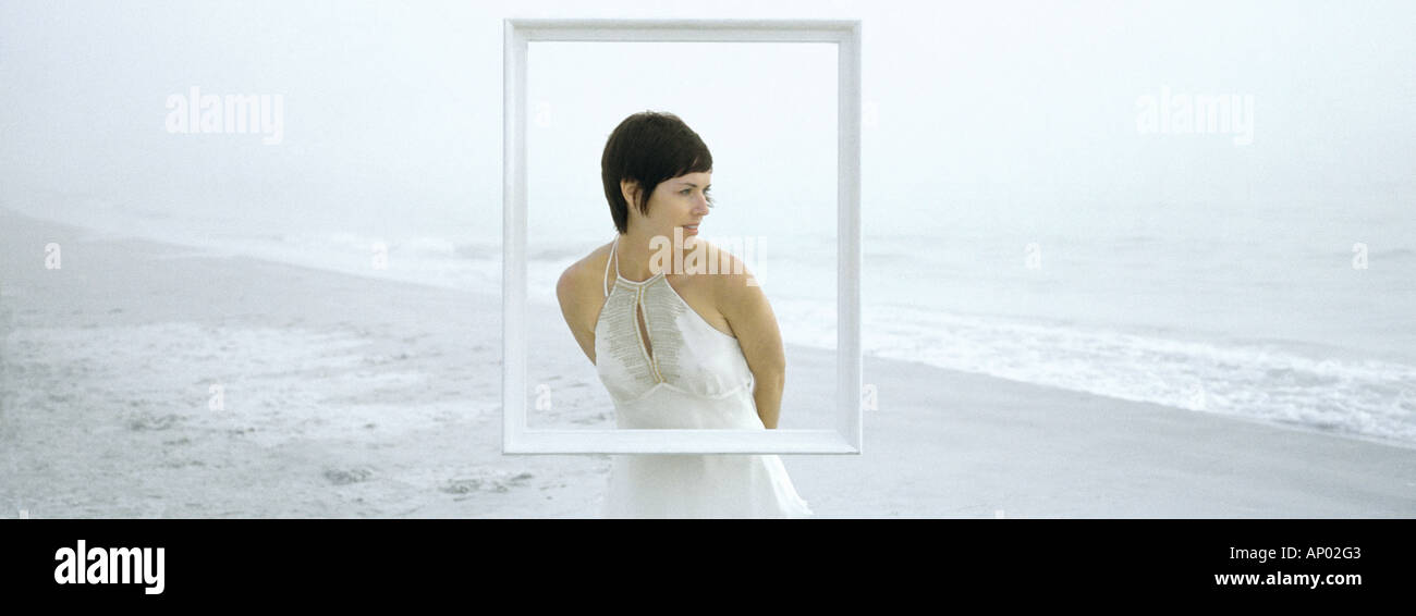 Woman standing on beach, behind frame Stock Photo