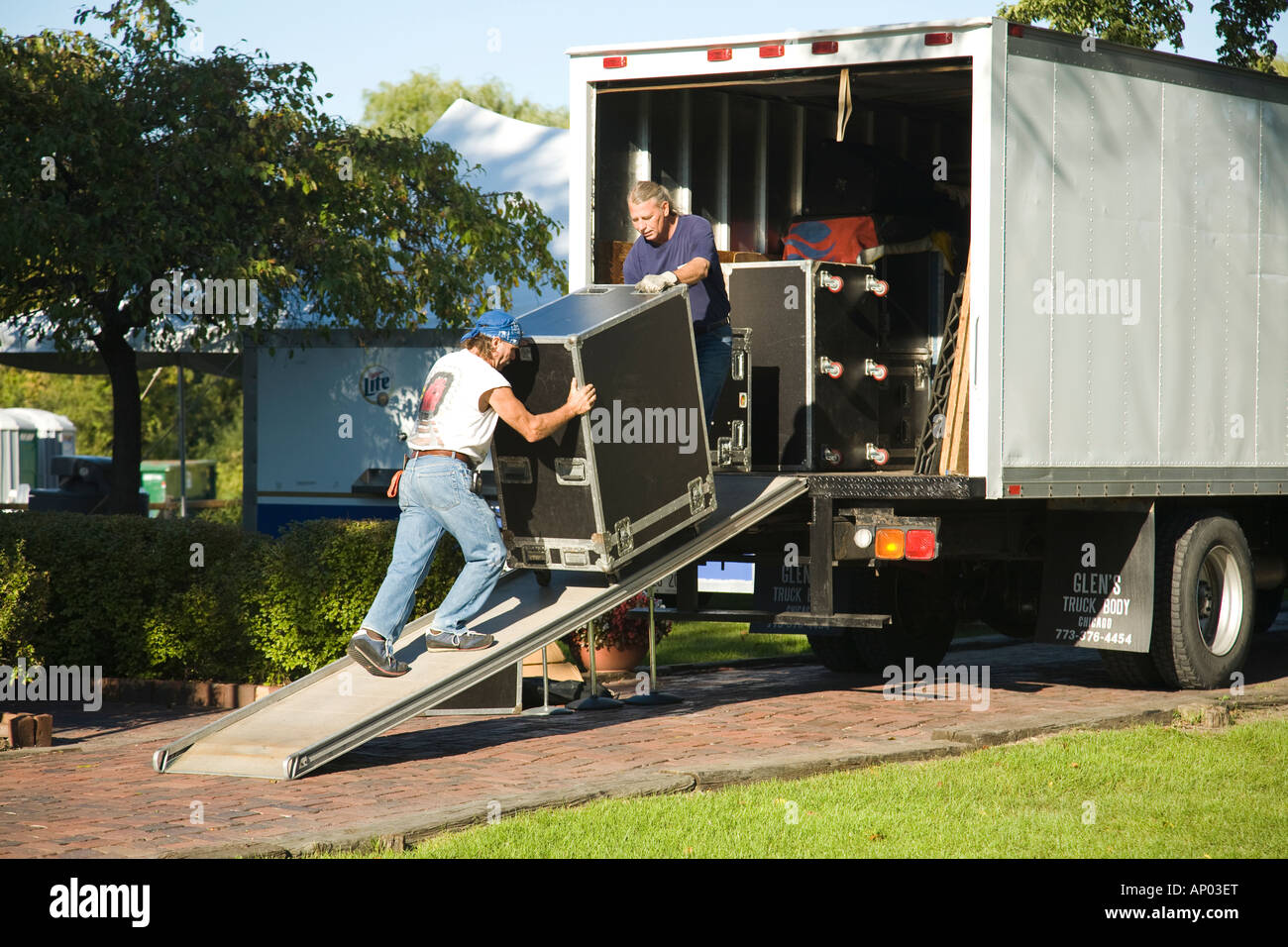 ILLINOIS Long Grove Two men unload speakers and large crates from truck using ramp Stock Photo