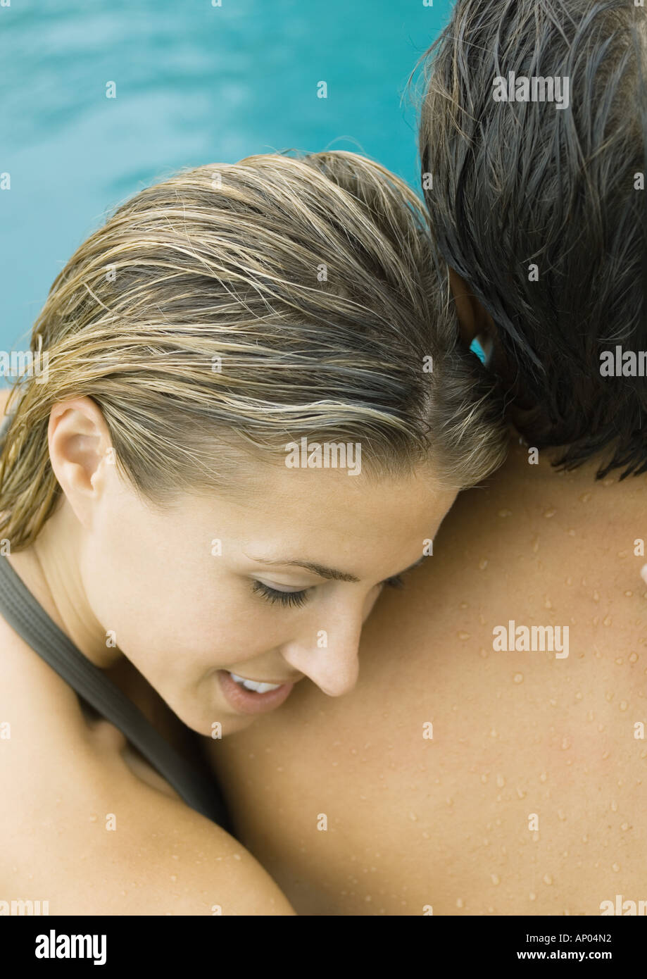 Couple near swimming pool, woman resting head on man's shoulder Stock Photo