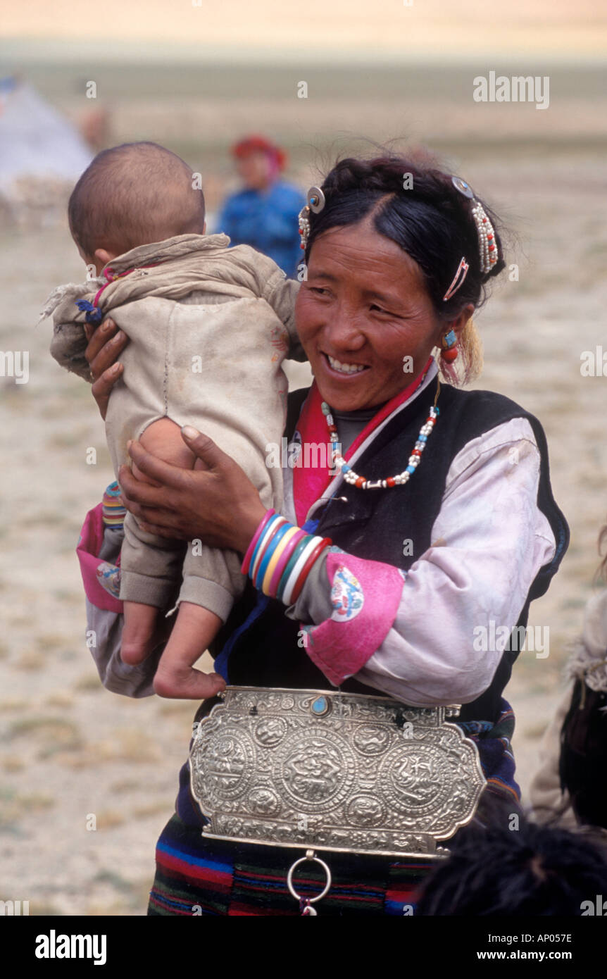 A FEMALE TIBETAN DROKPA Tibetan nomadic yak herder with her baby wearing SILVER CHUBA FASTENER TIBET Stock Photo