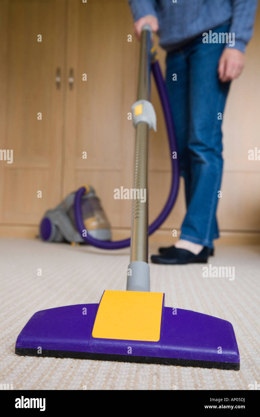 Woman sweeping room carpet with dual cyclone cylinder vacuum cleaner Stock Photo