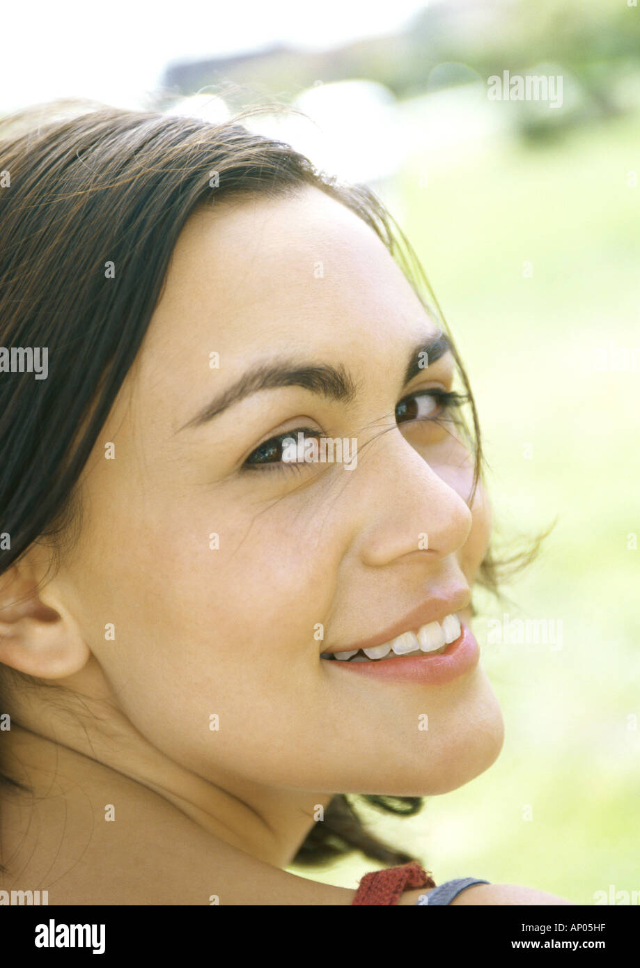 Young woman, looking over shoulder, smiling at camera Stock Photo