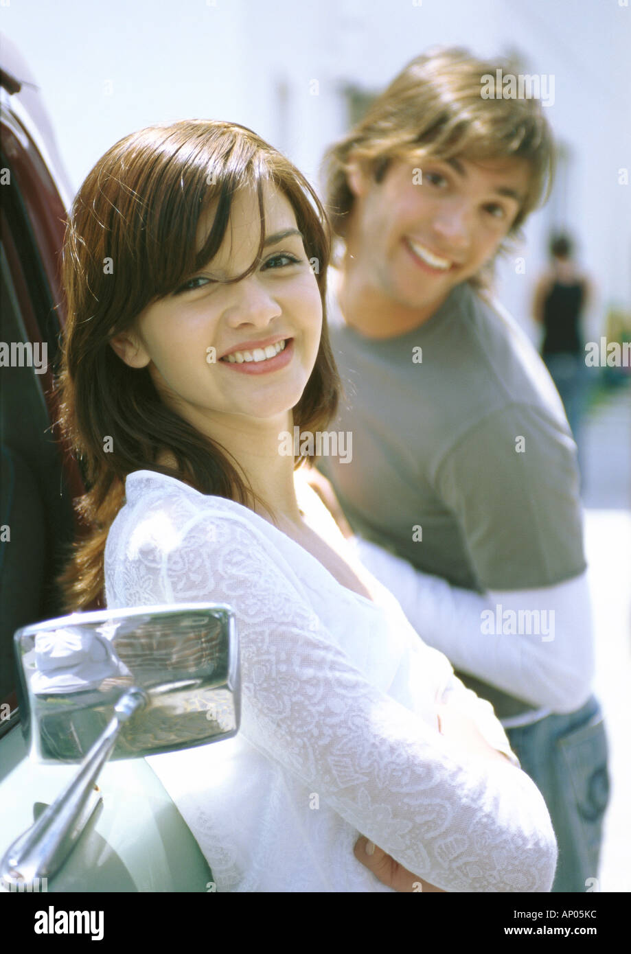 Young woman leaning against truck, man making face behind her Stock Photo