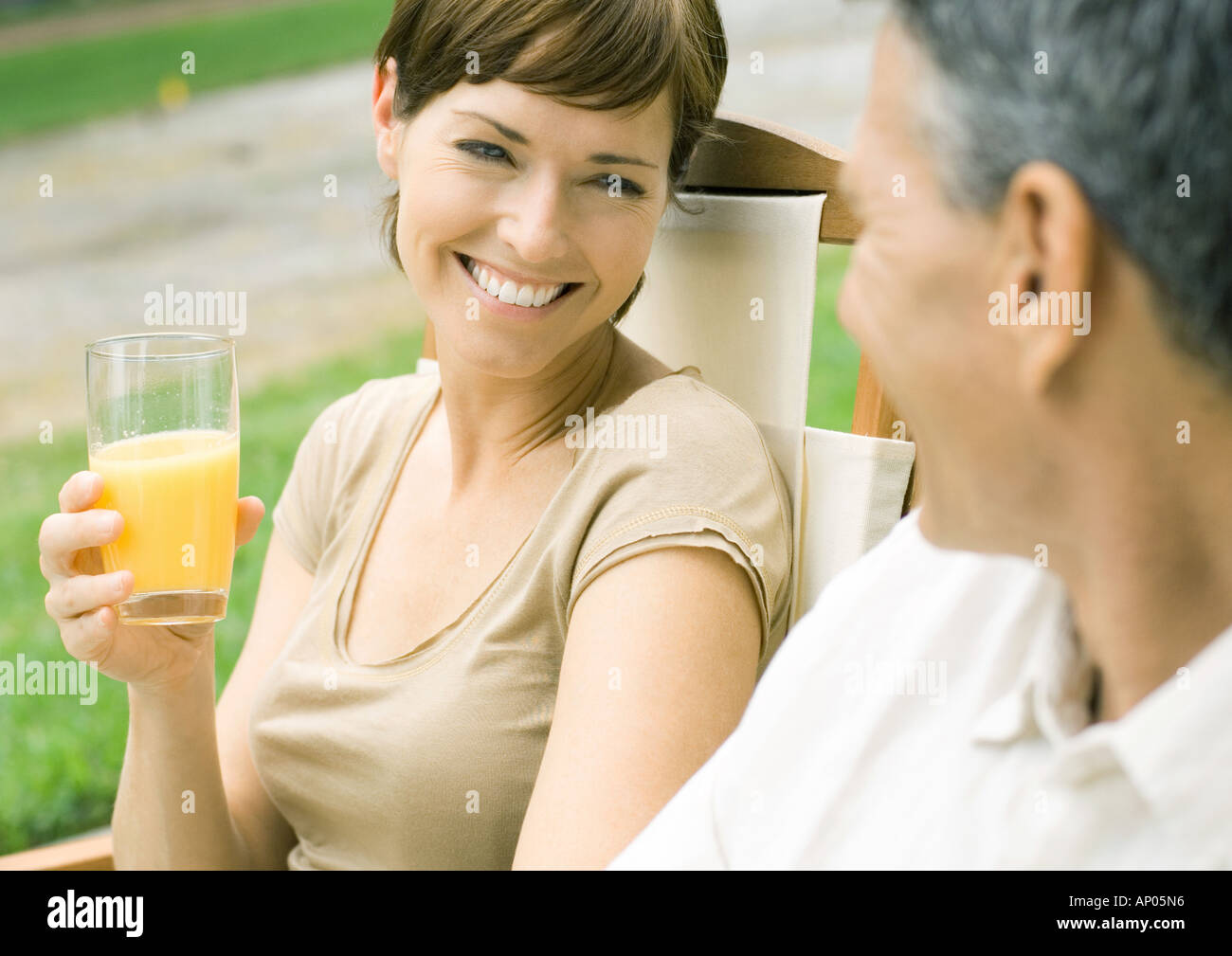 Woman holding glass of orange juice, looking at husband Stock Photo