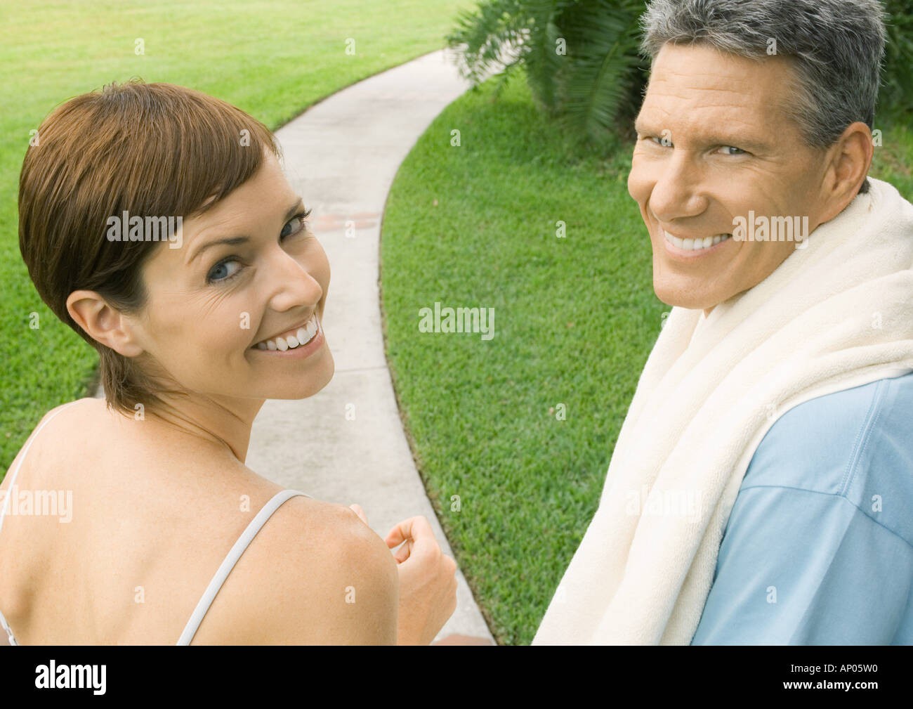 Mature couple in workout clothes, looking over shoulders at camera Stock Photo