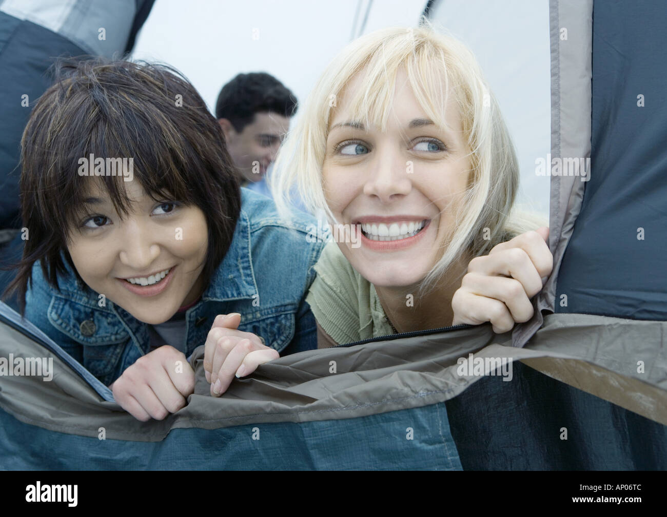 Two young female friends looking out of tent Stock Photo
