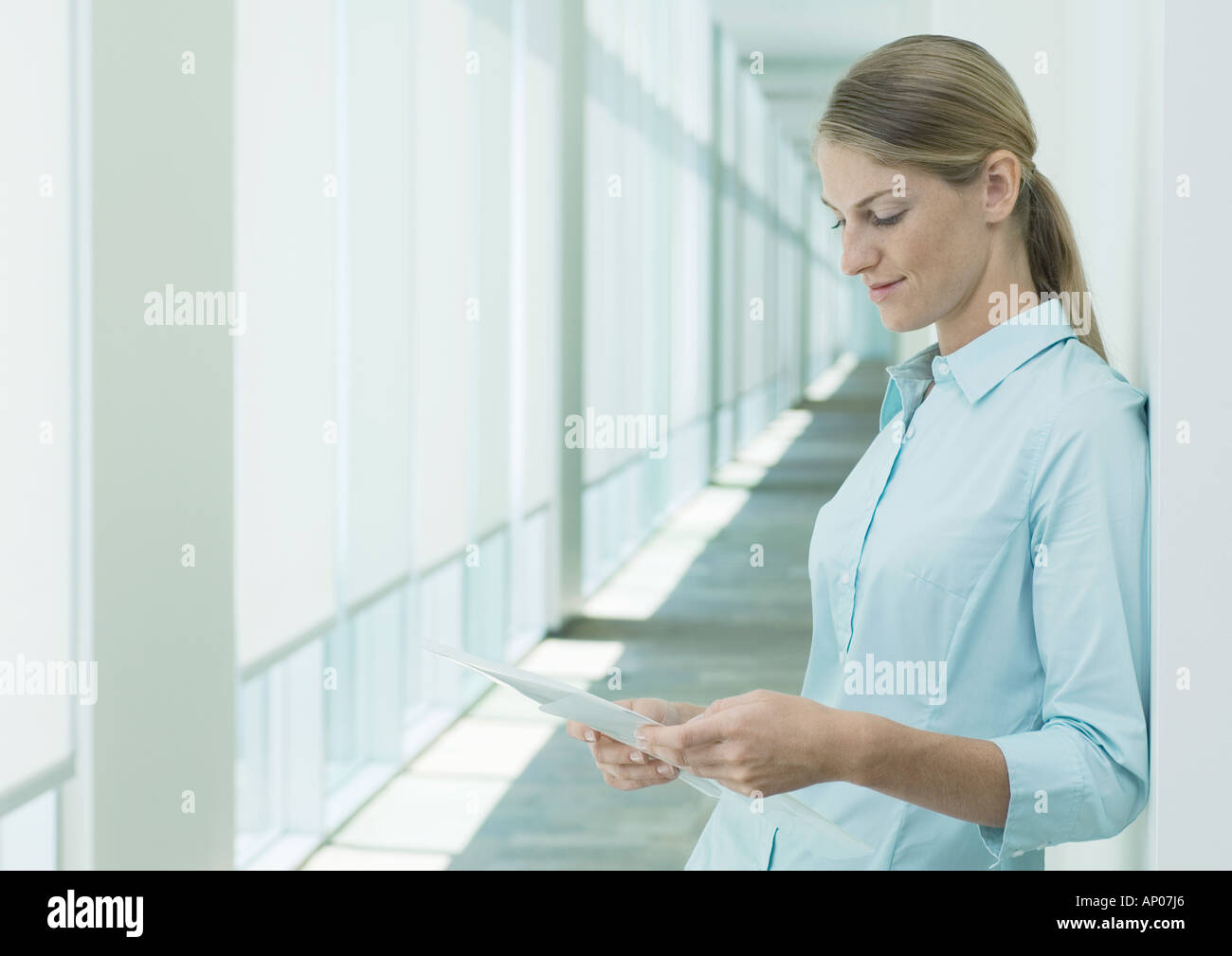 Woman reading document in hallway Stock Photo