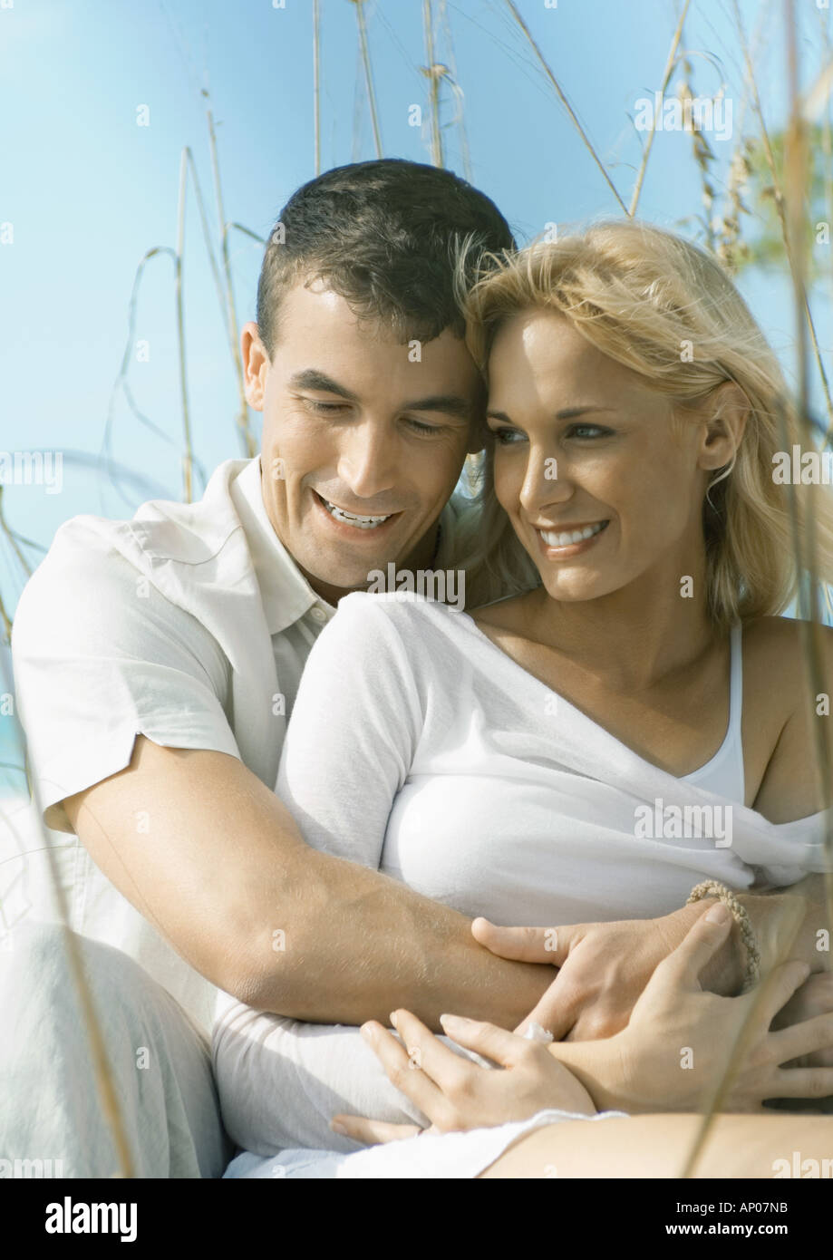 Man holding woman in dune grass Stock Photo