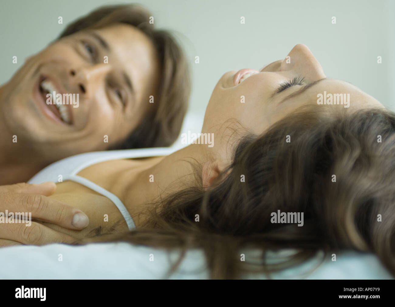 Couple lying in bed together, laughing Stock Photo