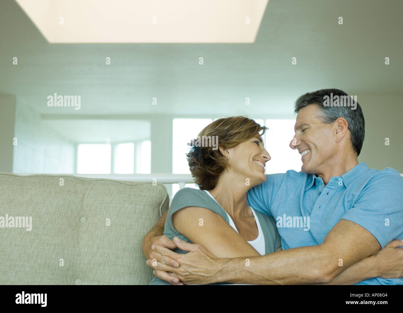 Mature couple embracing on sofa Stock Photo