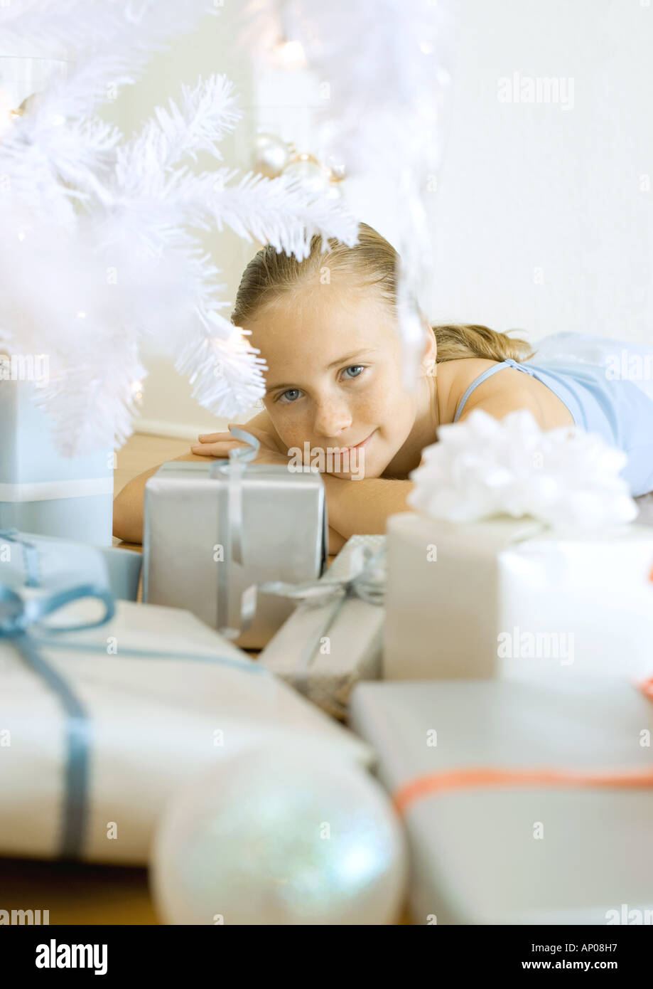 Girl lying under christmas tree among presents Stock Photo