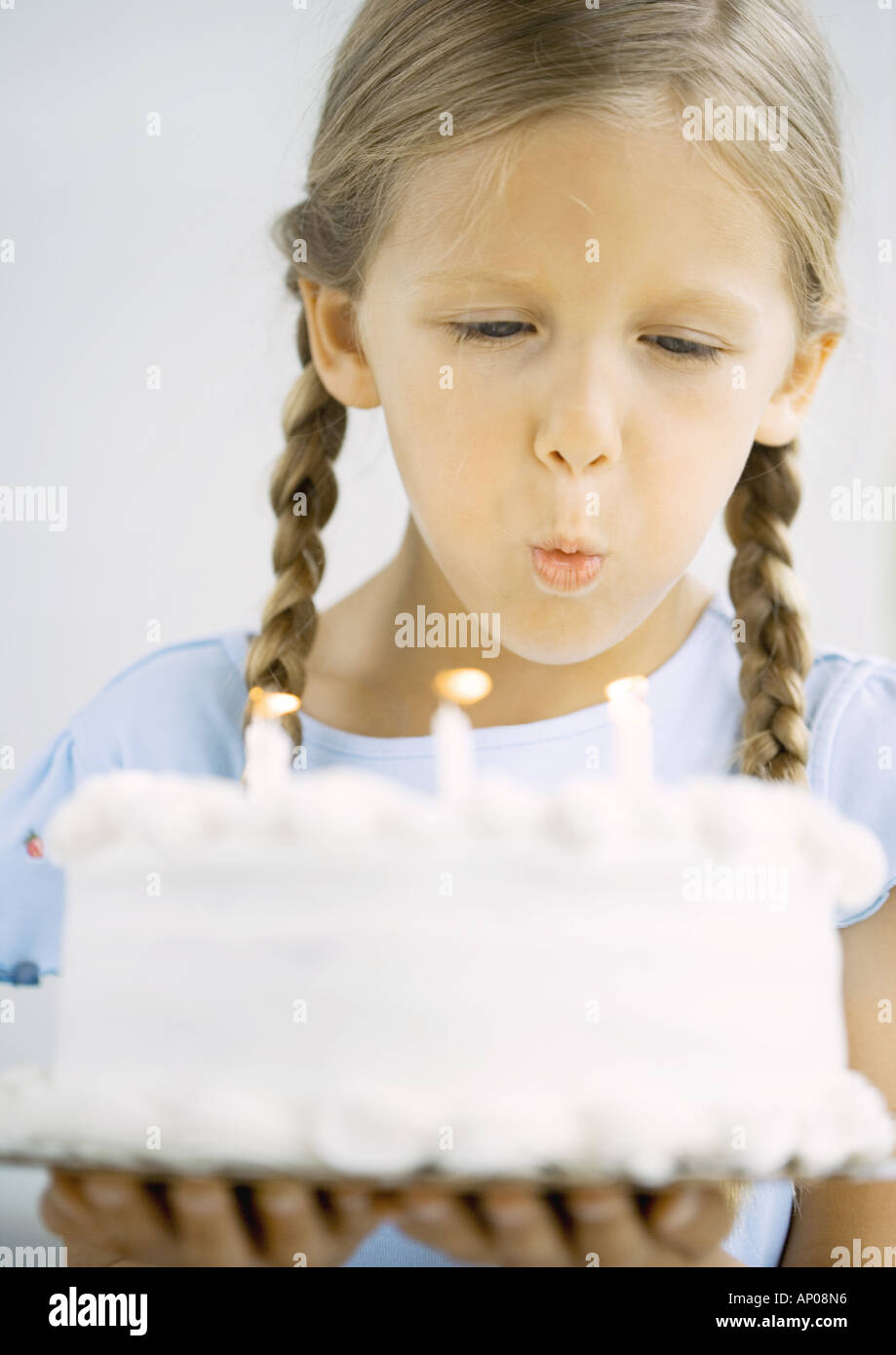 Little girl holding birthday cake, blowing out candles Stock Photo Alamy