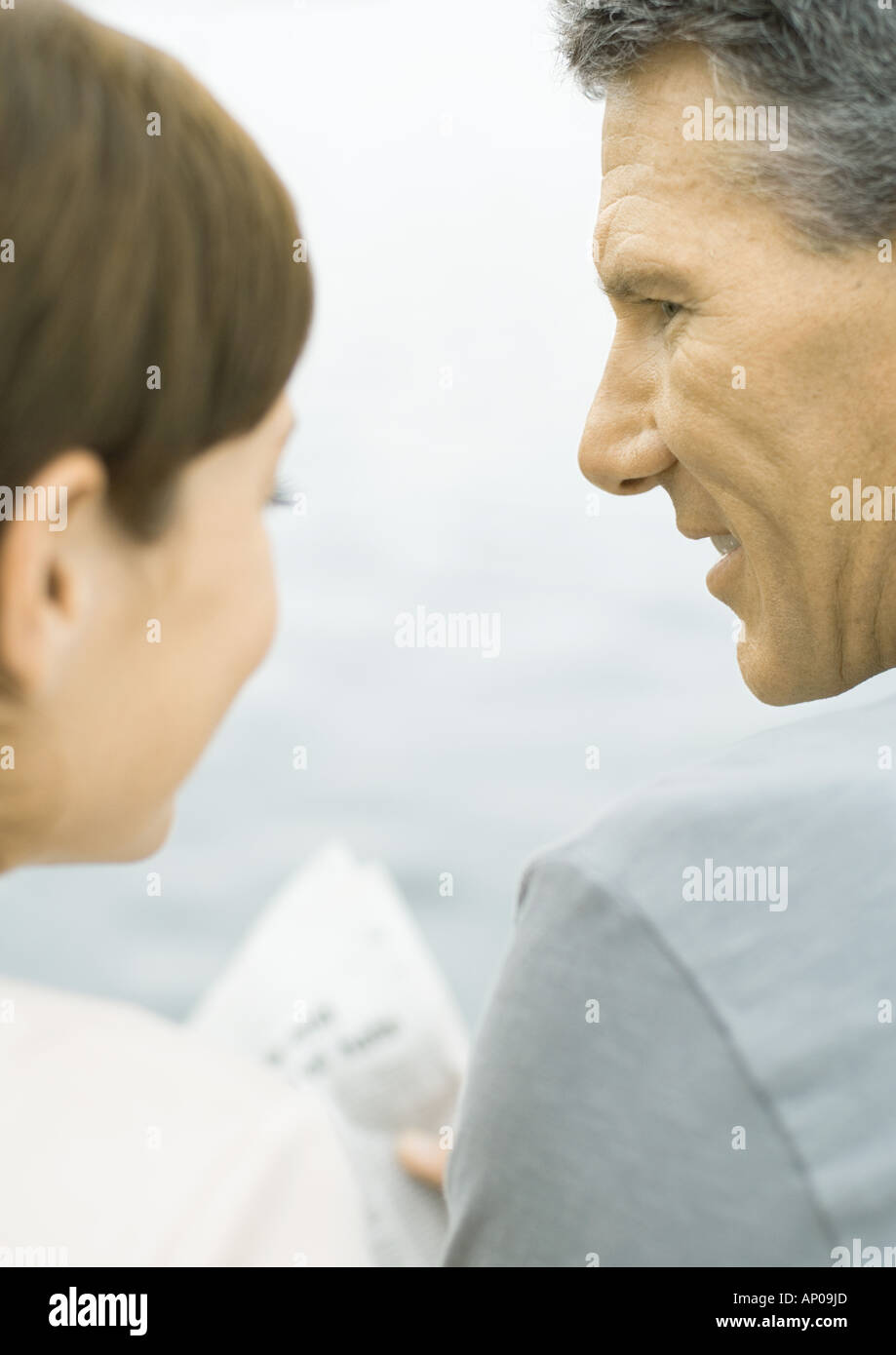 Couple reading newspaper together, water in background Stock Photo