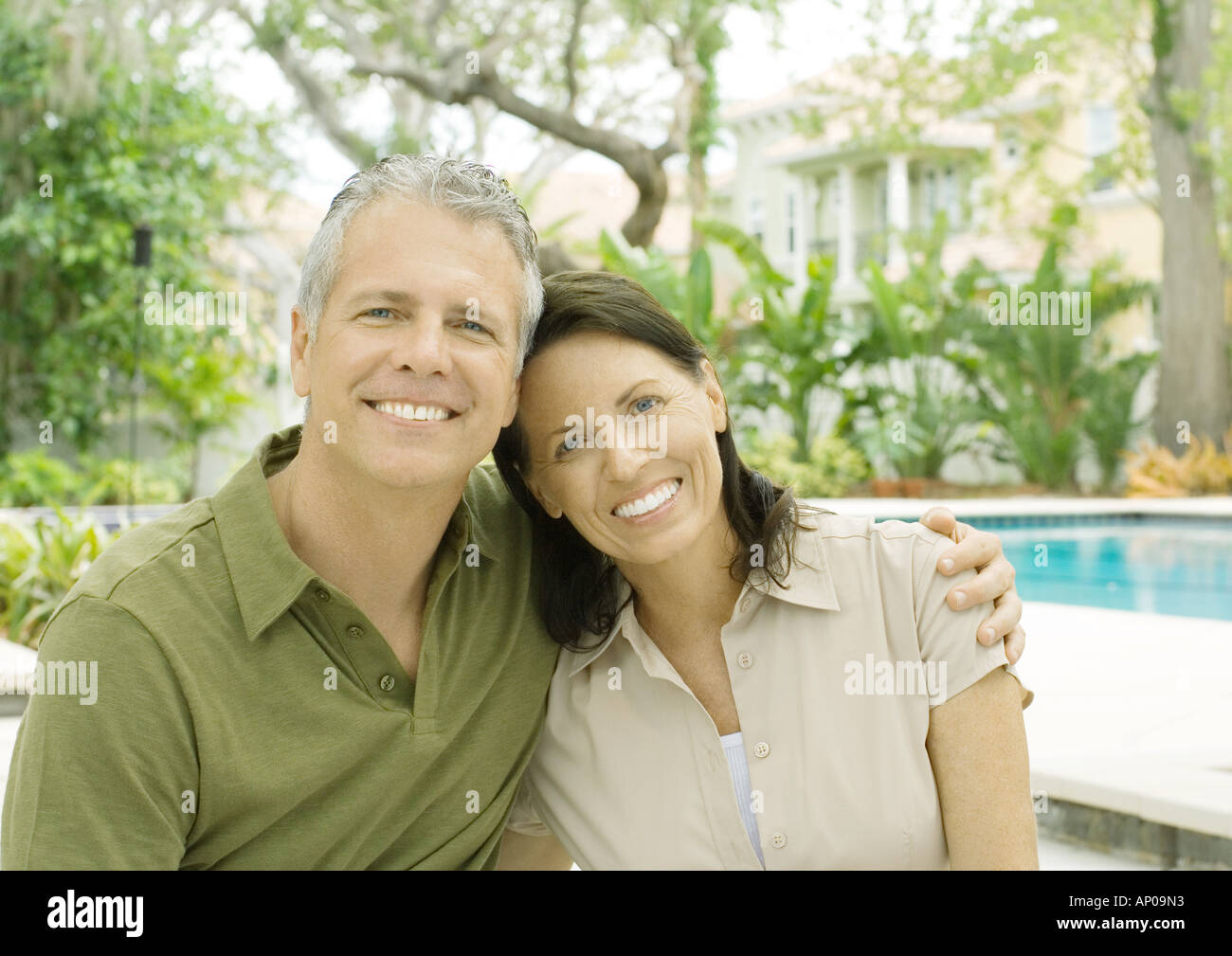 Couple standing in front of pool, smiling Stock Photo