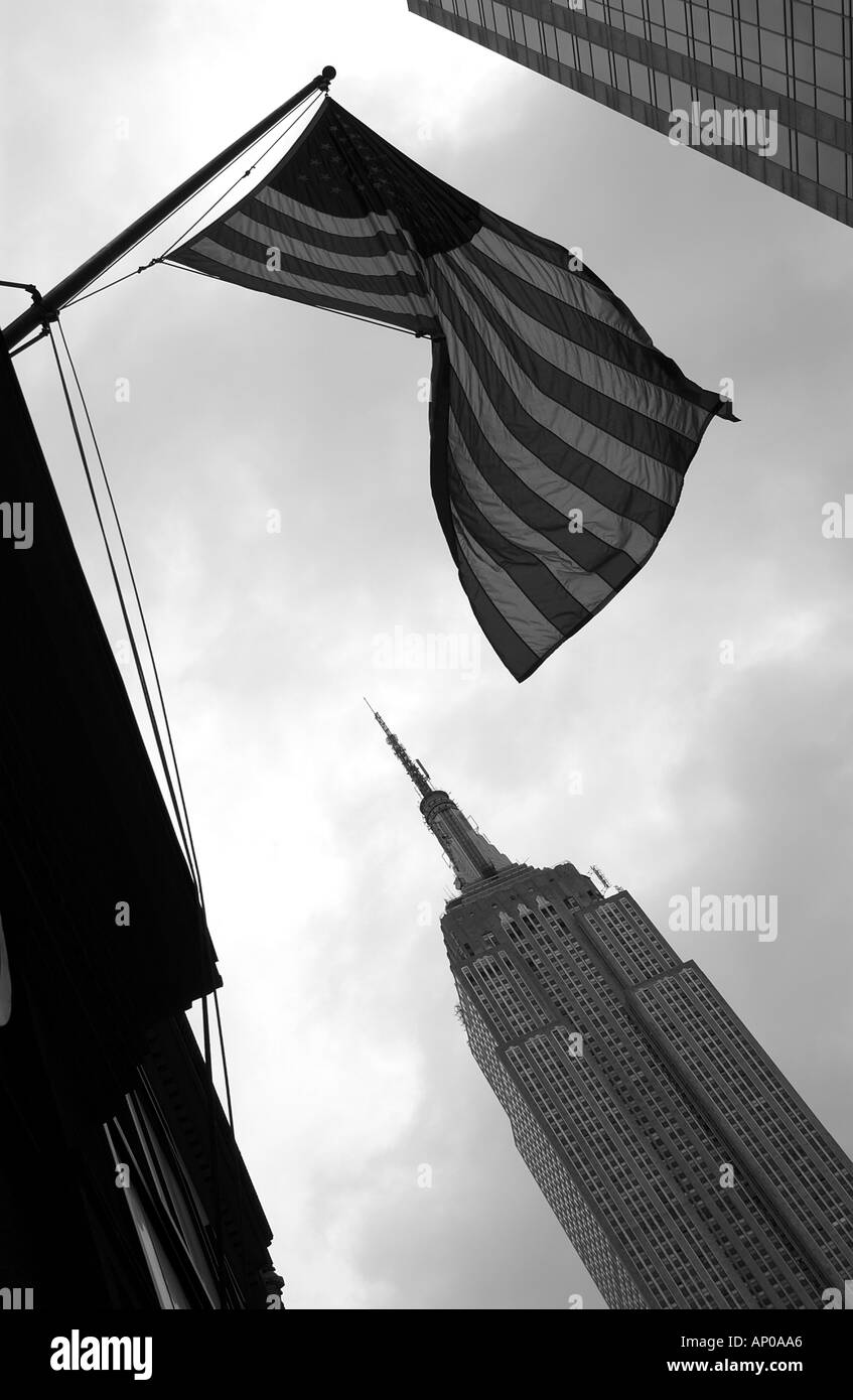 black and white view of the empire state building with an american stars and stripes flag in the foreground new york city USA Stock Photo