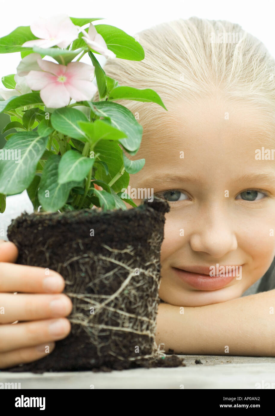 Girl with unpotted plant, smiling Stock Photo