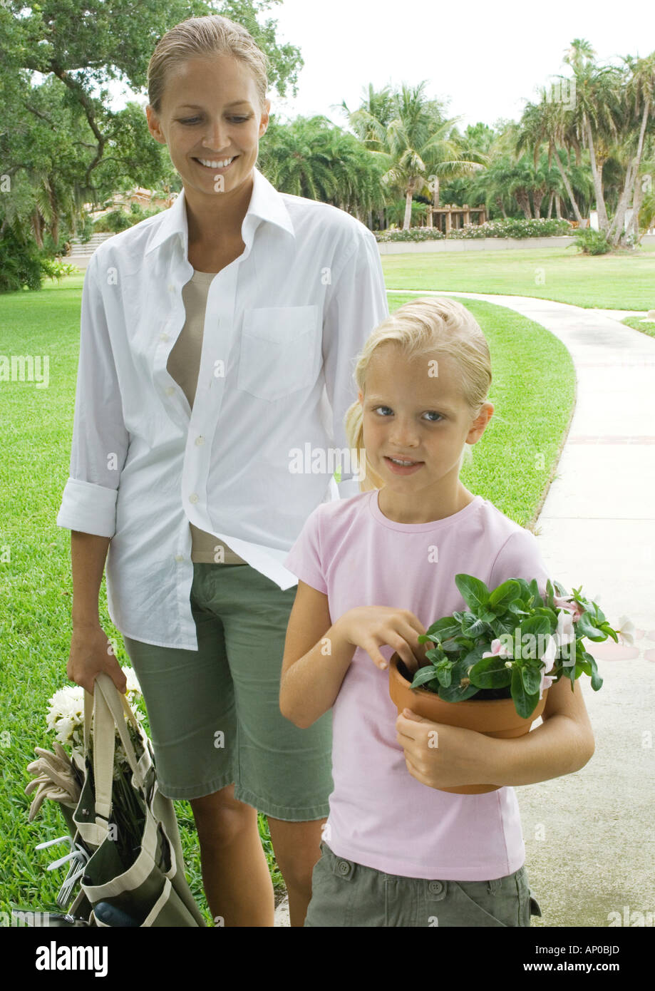 Woman and girl holding gardening supplies Stock Photo