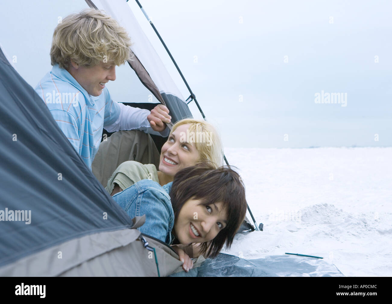 Three young adult friends looking out of tent Stock Photo