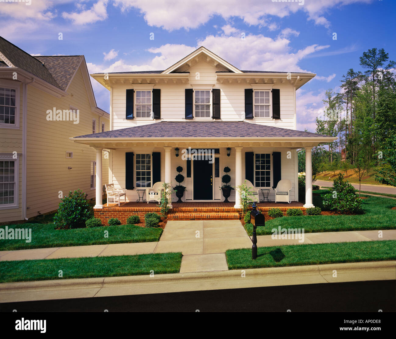 Simple two-story white house with wooden door, windows, and porch