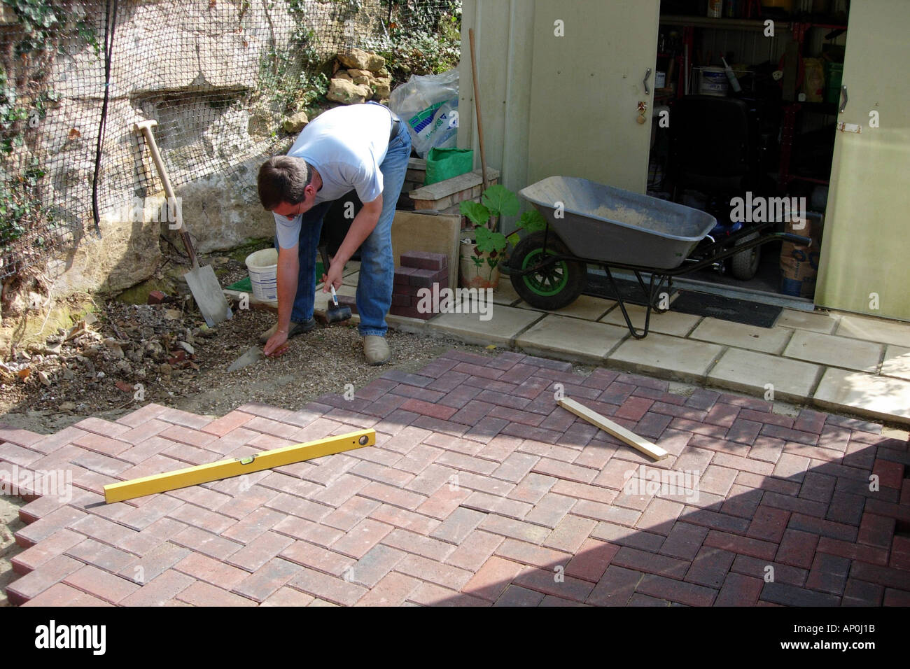 A Construction Worker Laying A Patio Using Block Paving Bricks