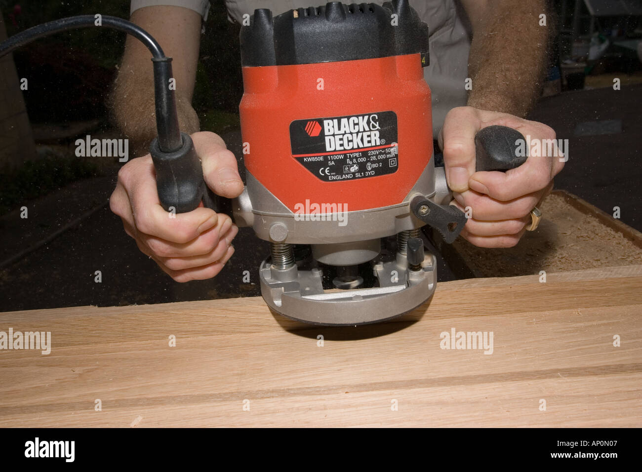 Craftsmans hands carefully controlling red Black Decker router on plank of  oak timber Stock Photo - Alamy