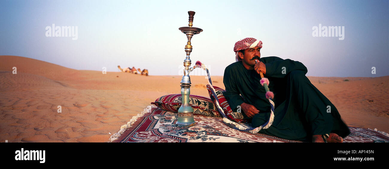Bedouin smoking waterpipe in the desert, Dubai, United Arab Emirates