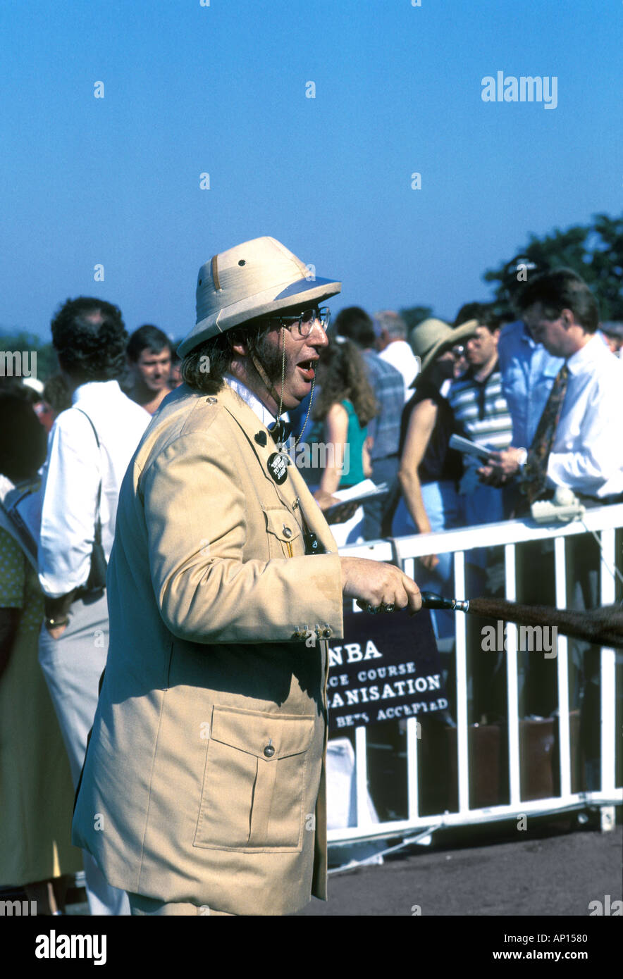 John McCririck TV horseracing pundit at age 53 beside the bookmakers' rails in the betting ring at the Sandown Park racecourse, Surrey, UK Stock Photo