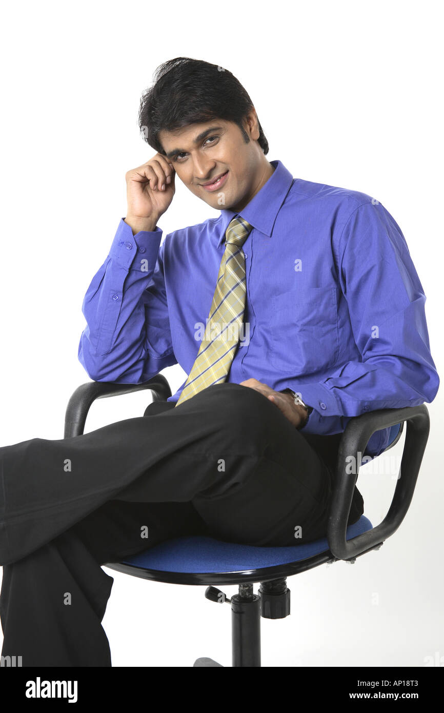 ANG200044 Executive touching his forehead with hand looking into camera and smiling Model release No 687M Stock Photo
