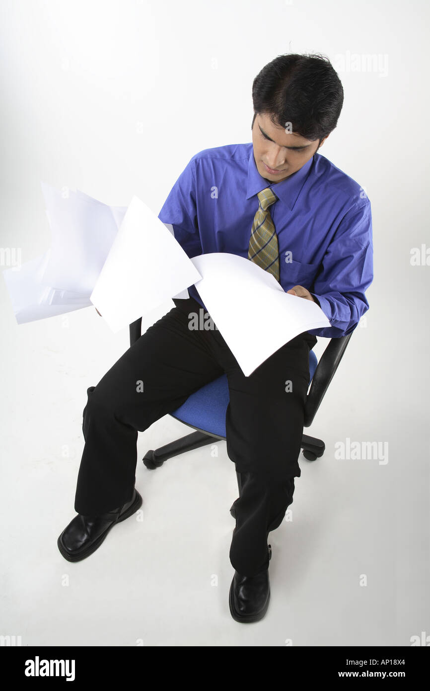 ANG200063 Executive resting on a chair throwing papers here and there frustrated Model release No 687M Stock Photo